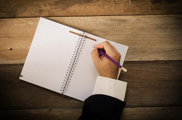 Hand skriva i öppen anteckningsbok på bordet — Stockfoto