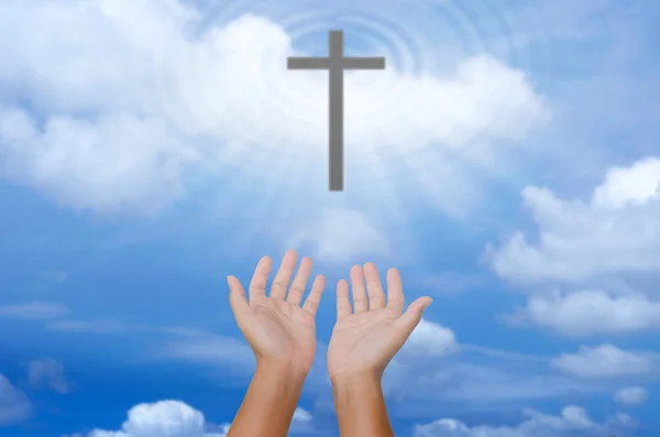 Otevřené ruce modlí kříž na rozostření pozadí oblohy. — Stock fotografie