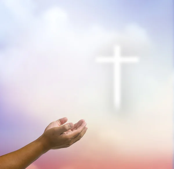Otevřené ruce modlí kříž na rozostření pozadí oblohy. — Stock fotografie