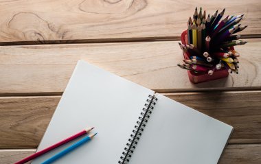 Ahşap masada renkli kalem ve çizim defteri