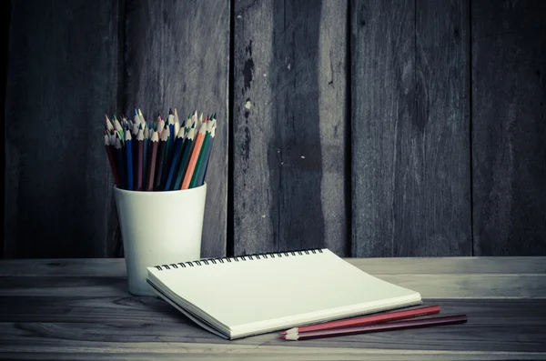 Lápiz de color y cuaderno de bocetos sobre mesa de madera — Foto de Stock