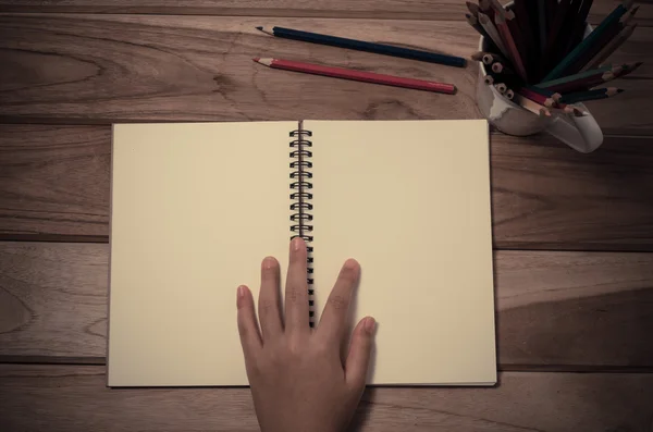 Mão e um caderno em uma mesa de madeira . — Fotografia de Stock