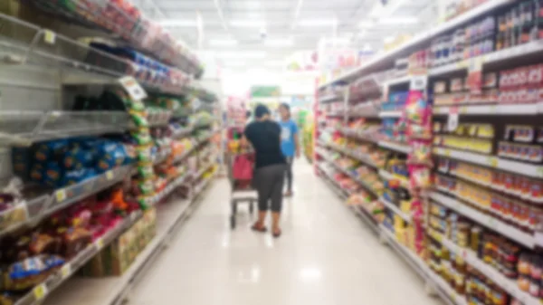 Personas caminando seleccionar productos en el desenfoque del supermercado . — Foto de Stock