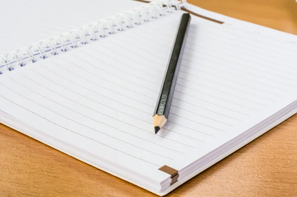 Notebook em branco com lápis na mesa de madeira — Fotografia de Stock