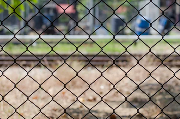 Metal mesh wire fence with blur factory background — Stock Photo, Image