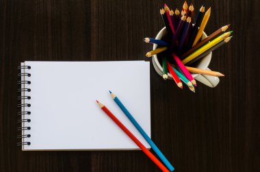 Ahşap masada renkli kalem ve çizim defteri