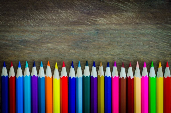 Línea de lápices de colores sobre fondo de madera — Foto de Stock