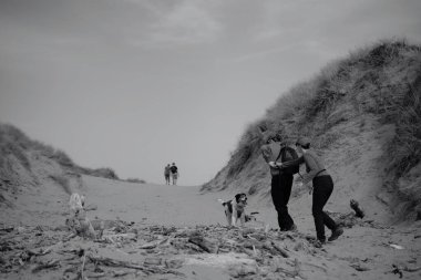 Merthyr Mawr kum tepeleri ve doğa rezervi. Gençler tekrar bir araya gelip kum tepelerini aşıp sırt çantaları, sörf tahtaları ve gün boyu içeceklerle kumsala yürümekten keyif alıyorlar.