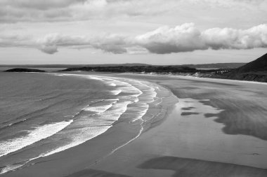 Gower Yarımadası 'ndaki Worm' s Head 'deki uçurum yüzeyi altın kum ve dalgaların aktığı Llangennith' teki muhteşem sahili incelemek için mükemmel bir görüş açısı sunuyor. İnsanlar manzaranın tadını çıkarıyor