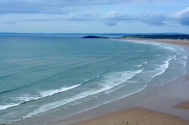 Gower Yarımadası 'ndaki Worm' s Head 'deki uçurum yüzeyi altın kum ve dalgaların aktığı Llangennith' teki muhteşem sahili incelemek için mükemmel bir görüş açısı sunuyor. İnsanlar manzaranın tadını çıkarıyor