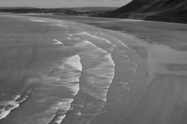 Gower Yarımadası 'ndaki Worm' s Head 'deki uçurum yüzeyi altın kum ve dalgaların aktığı Llangennith' teki muhteşem sahili incelemek için mükemmel bir görüş açısı sunuyor. İnsanlar manzaranın tadını çıkarıyor