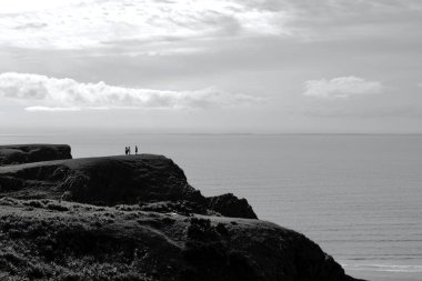 Gower Yarımadası 'ndaki Worm' s Head 'deki uçurum yüzeyi altın kum ve dalgaların aktığı Llangennith' teki muhteşem sahili incelemek için mükemmel bir görüş açısı sunuyor. İnsanlar manzaranın tadını çıkarıyor