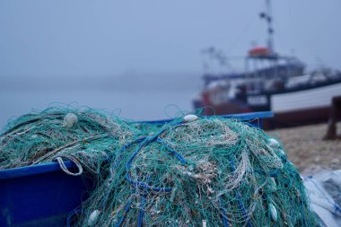 Stade Hastings 'de sisli, sisli bir gün ve yerel balıkçı tekneleri bir sonraki yüksek gelgite kadar kiremitli plaja çekildi. Deniz sisi gizemli, atmosferik görünümlü bir manzara yaratır.