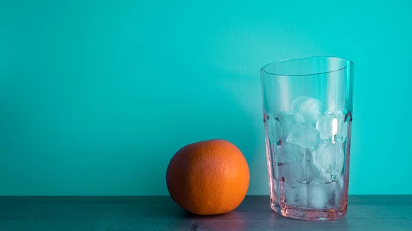 Bright orange with a glass of ice on a turquoise background.