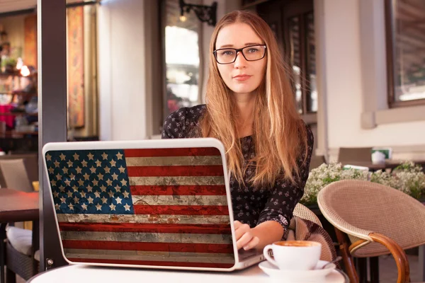 Женщина сидит в кафе с блокнотом с американским флагом — стоковое фото