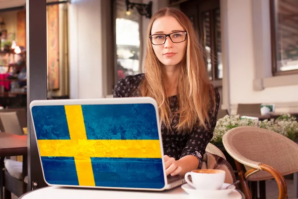 İsveç bayrağı ile defter ile bir kafede oturan kadın