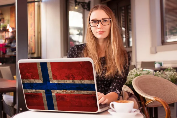 Женщина сидит в кафе с блокнотом с норвежским флагом — стоковое фото