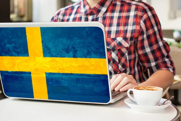 Kahve ile bir kafe ve defter İsveç bayrağı ile oturan adam