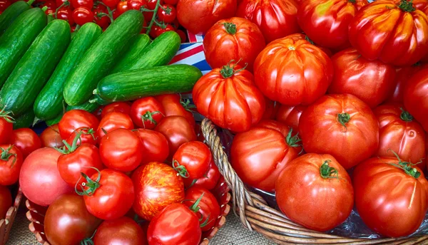 Uma abundância de tomates vermelhos e pepinos em cestas — Fotografia de Stock