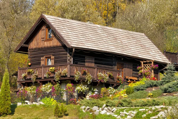 Traditional mountain wooden cottage in autumn colors on a hill