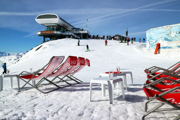 Les Menuires, Alps, França, 18 de março de 2014: Esquiadores e snowboarders no topo do teleférico em Three Valleys Ski Resort ao lado do bar lounge de esqui ao ar livre — Fotografia de Stock