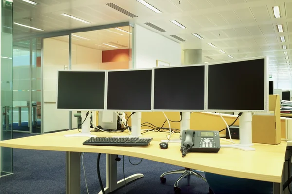 Escritorio de ordenador con monitores, teclado y teléfono en una oficina moderna — Foto de Stock