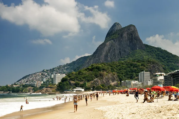 As pessoas estão relaxando, tomando sol, andando, brincando no mar na praia de Ipanema, no Rio de Janeiro, em um dia quente e ensolarado — Fotografia de Stock