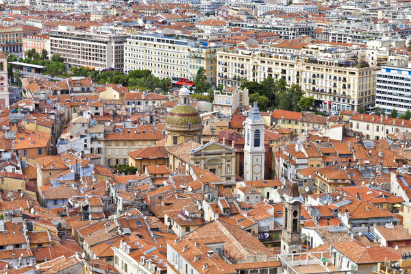 Daytime cityscape of historic Nice in French Riviera with red roofs of the old town, churches and parks.