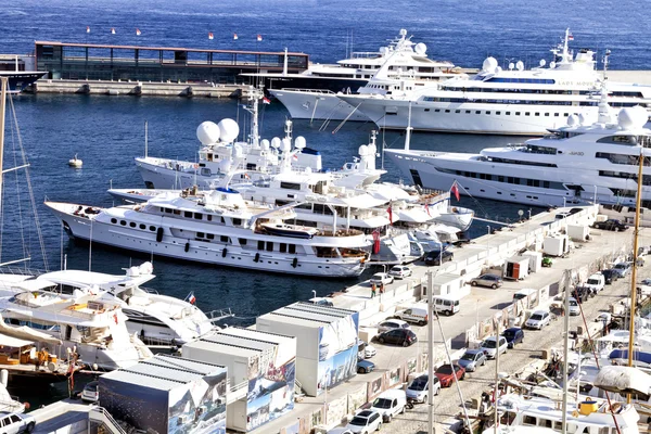 Super yates, veleros y barcos atracados en Monte Carlo, puerto de Mónaco, junto a un muelle con coches aparcados . — Foto de Stock