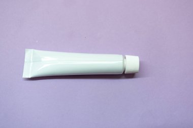 Eflatun arka planda kozmetik için beyaz tüpler. Düz.