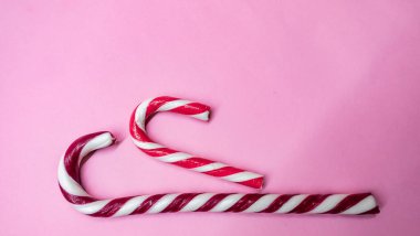 Noel şekeri, pembe arka planda baston şeklinde lolipoplar.