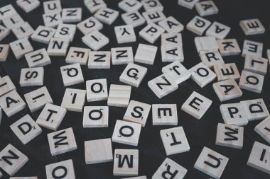 Chon Buri, Tayland, 15 NOV '2020. Ahşap arka planda bir yığın scrabble harfi. Tahta arka planda çivilenmiş alfabe bloğu. Kelime taşları. Harf ve renkli kalemler tahtadan siyah arkaplanda izole edilmiş..