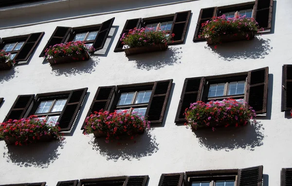 Tradycyjne Austriackie Okna Białej Ścianie Kolorowymi Pudełkami Kwiatów — Zdjęcie stockowe