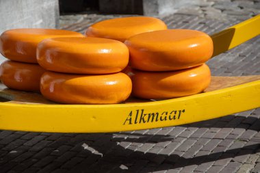 Sarı ahşap tepside parlak turuncu kabuklu yuvarlak peynir tekerlekleri.