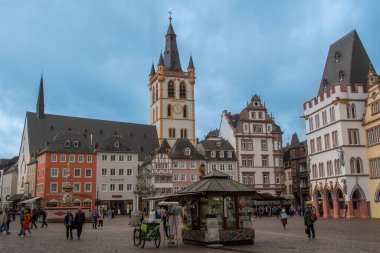 Trier, Almanya 25 Eylül 2024, Trier 'deki tarihi pazar meydanı St. Gangolf Kilisesi, renkli eski kasaba evleri ve gündüz vakti merkez market çeşmesi