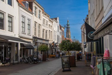 Middeburg, Hollanda, 21 Mart 2025, tarihi Middelburg kasabasında büyüleyici yaya bölgesi, açık mavi gökyüzü altında çarpıcı bir kilise kulesi manzarası var..