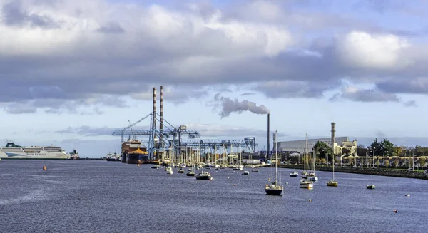 Dublin Limanı, İrlanda manzaralı, çalışır vaziyette bir vinci olan yolcu feribotu, küçük tekneler ve uzaktaki East Link Ferry Köprüsü ve yeni yakma fırını.. 