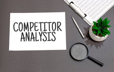 COMPETITOR ANALYSIS işareti ile yazılmış büyüteç, hesap makinesi, kalem, bitki ve defter üst görünümü