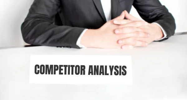 사업가가 테이블에 앉아서 텍스트 Competitor Analysis — 스톡 사진