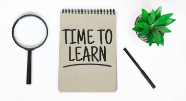Bir büyüteç, beyaz bir masanın üzerinde boş kahverengi bir defter. İşaret Öğrenme Zamanı