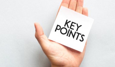 Pembe gömlekli bir iş adamının elinde kağıt kartvizit var. Üzerinde KEY POINT yazılı. Beyaz arka planda izole edilmiş yakın plan.