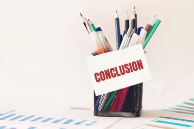 Ofisteki kalem kutusunda CONCLUSION yazan kart. Diyagram ve beyaz arkaplan