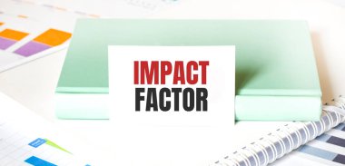 Beyaz büyük not defteri, yeşil kitap ve kâğıt üzerinde IMPACT FACTOR yazılı finansal diyagram. İş konsepti