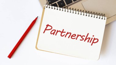 Laptop, kırmızı kalem ve beyaz arkaplanda metin ortaklığı olan not defteri