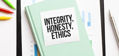 Beyaz büyük not defteri, yeşil kitap ve kâğıt tabaka üzerinde mali diyagram INTEGRITY, HONESTY, ETHICS. İş konsepti