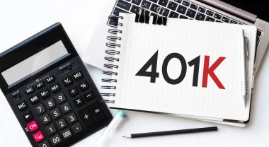 Dizüstü bilgisayarın klavyesi, hesap makinesi, kalem ve not defteri beyaz arkaplanda 401k metni ile