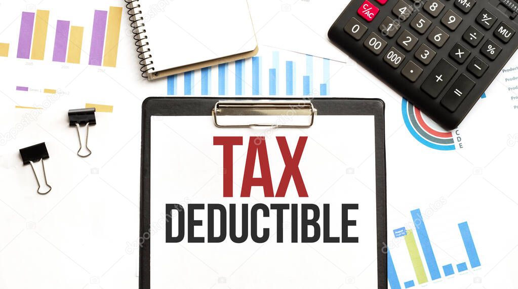 Paper plate with text TAX DEDUCTIBLE. Diagram, calculator, notepad and white background