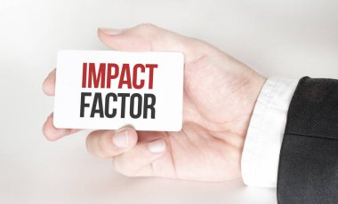Üzerinde IMPACT FACTOR yazan bir kart tutan işadamı