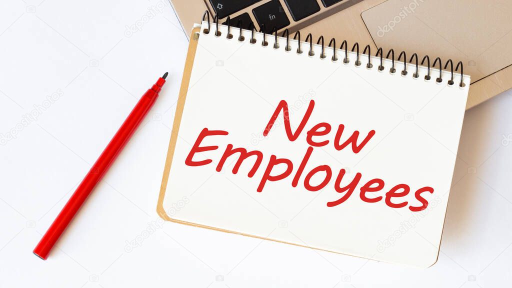 Laptop, red pen and notepad with text NEW EMPLOYEES in the white background