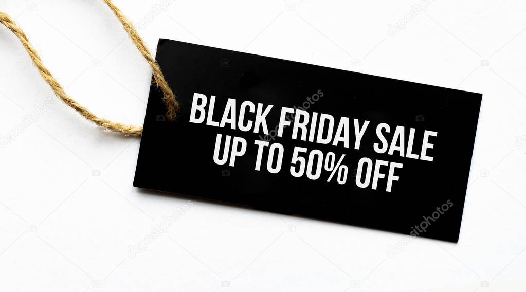 BLACK FRIDAY SALE UP TO 50 percents text on a black tag on a white paper background